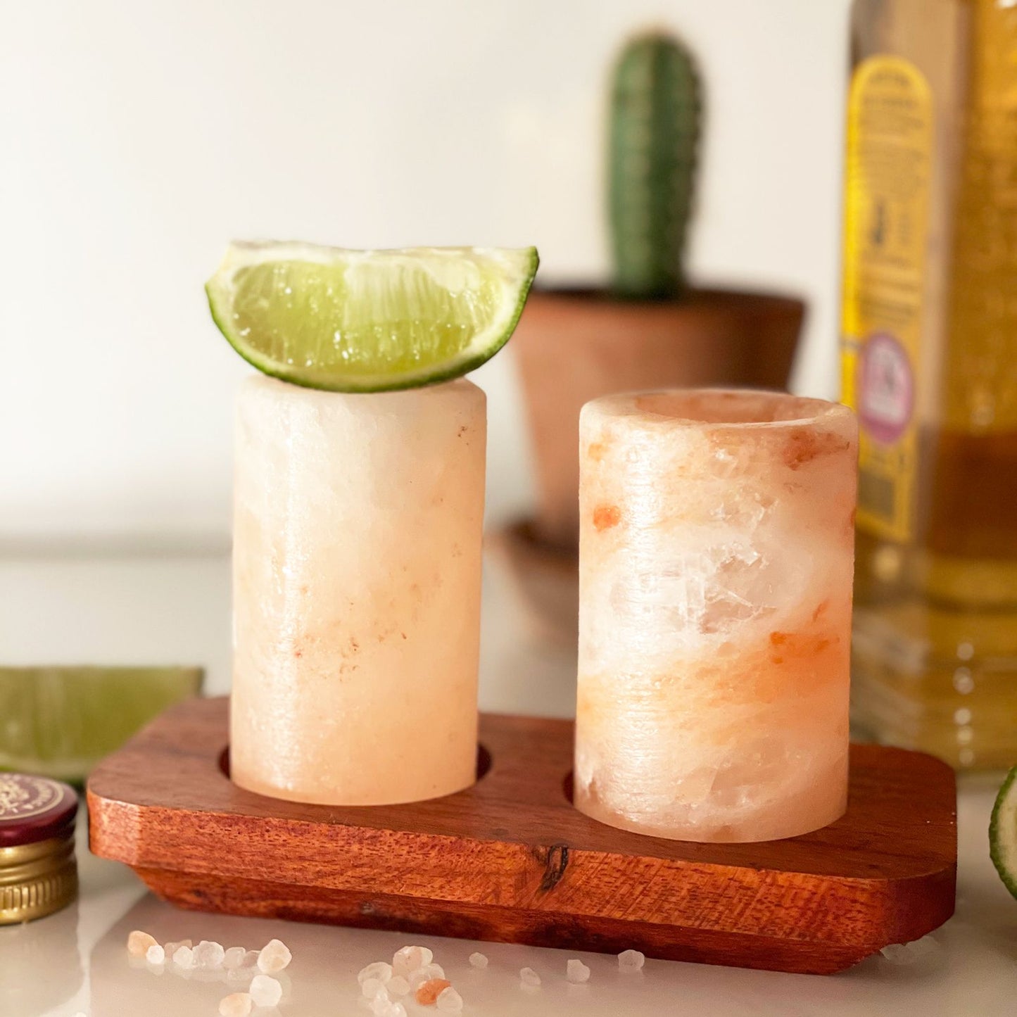 Two Himalayan salt shot glasses on a wooden serving stand with gift box