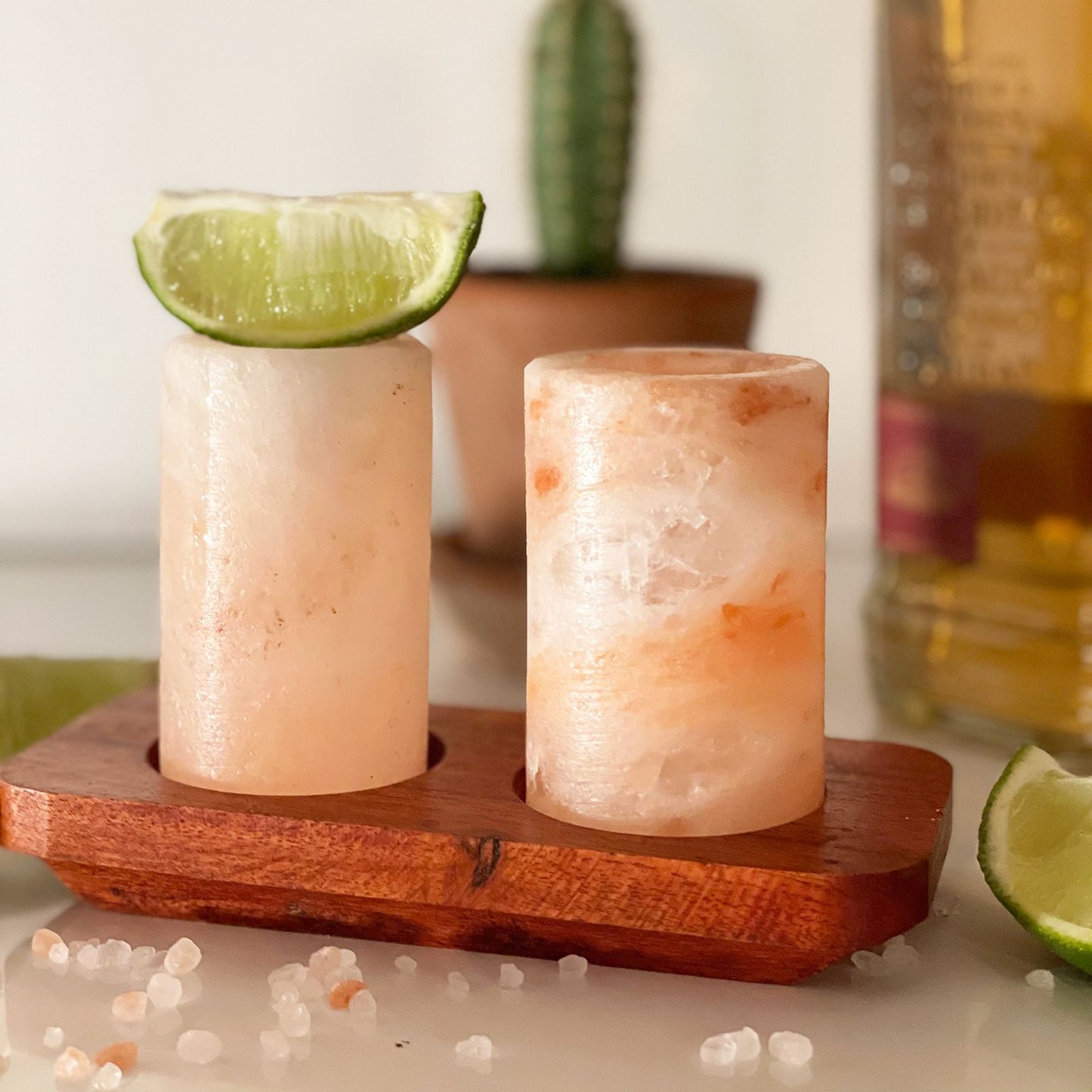 Two Himalayan salt shot glasses on a wooden serving stand with gift box