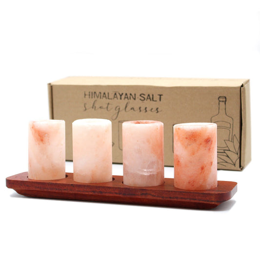 Four Himalayan salt shot glasses on a wooden serving stand with gift box